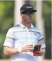  ?? Tyler Lecka / Getty Images ?? With his ball in a bunker, RBC Heritage co-leader Graham DeLaet looks over his notes for the best approach on the 15th hole.
