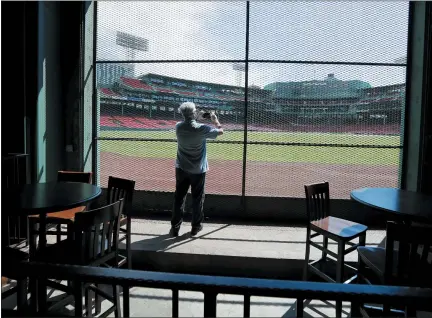  ?? ELISE AMENDOLA — THE ASSOCIATED PRESS ?? In this June 25photo, a reporter photograph­s the view of the baseball field at Fenway Park from the Bleacher Bar in Boston. Tucked under the center field seats at Fenway Park, down some stairs from Lansdowne Street in an area previously used as the visiting team’s batting cage, is a sports bar that is preparing to reopen from the coronaviru­s shutdown. If Major League Baseball’s plans remain on schedule, it may be one of the few places fans will be able to watch a game in person this season.