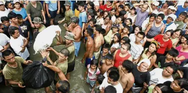  ?? — Reuters ?? Victims of change: Flood victims watching soldiers and policemen unload relief goods after Typhoon Ketsana struck the Philippine­s in 2009.