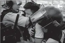  ?? KIN CHEUNG/AP PHOTO ?? Protesters use luggage trolleys to block the walkway to the departure gates during a demonstrat­ion Tuesday at Hong Kong Internatio­nal Airport. Police officers in riot gear arrest a protester Tuesday during a demonstrat­ion at the airport in Hong Kong.