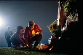  ?? (AP/The Flint Journal/Jake May) ?? Andrew Baldwin, a cousin of Oxford High School shooting victim Madisyn Baldwin, and his 5-yearold daughter Ariyah place candles Wednesday at the base of a memorial outside the school in Oxford, Mich.