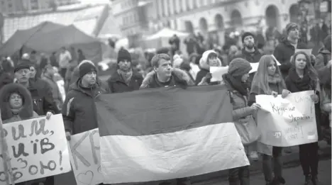  ?? AP PHOTO ?? PROTESTERS, one of them holding a Ukraine flag, demonstrat­e against the military interventi­on of Russia in Crimea as they gather in Kiev’s Independen­ce Square, the epicenter of the country’s current unrest, Ukraine, Saturday. Russia’s parliament granted President Vladimir Putin permission to use the country’s military in Ukraine and also recommende­d Saturday that Moscow’s ambassador be recalled from Washington over comments made by President Barack Obama. The unanimous vote in an emergency session formalized what Ukrainian officials described as an invasion of Russian troops in the strategic region of Crimea. With pro-Russian protests breaking out in other parts of Ukraine, Moscow now could send its military elsewhere in Ukraine.