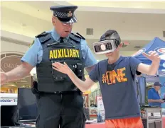  ?? MICHELLE ALLENBERG/WELLAND TRIBUNE ?? Sgt. Rudy Sobschaky assists Tennessee Matyas, 12, during an impaired driving roadside test using a virtual reality simulator at Seaway Mall Saturday.