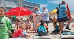  ??  ?? Surfers, parents, and coaches wait for the start of an adaptive surfing event at Muizenberg beach.