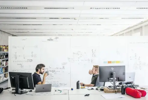  ?? ANGEL GARCIA / BLOOMBERG ?? Employees discuss project notes on a whiteboard inside Telefonica SA’s Alpha innovation facility in Barcelona.