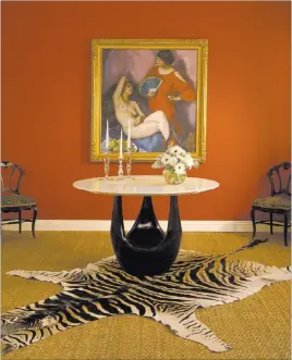  ??  ?? The feminine curves and shapes of the modern cast bronze table, the 19th-century antique side chairs, the Steuben teardrop crystal candle holders and the dark red wall complement and highlight this Edouard Vysekal painting.