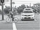  ??  ?? A Waymo self-driving minivan stops for a cyclist at its test facility. WAYMO