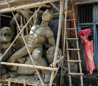  ?? ?? A woman hangs clothes outside her house Sept. 18 beside an unfinished idol of Hindu goddess Durga ahead of Durga Puja festival at Kumortuli.