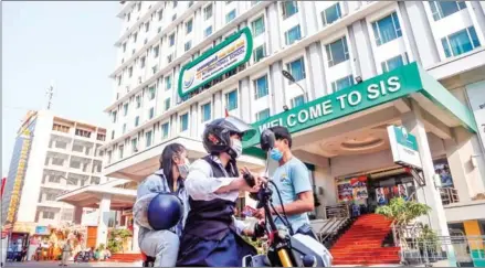  ?? HENG CHIVOAN ?? Students drive past a private school in Doeum Kor commune of Phnom Penh’s Tuol Kork district on Monday.