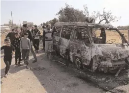  ?? — AP ?? Kids look at a destroyed van near the village of Barisha, in Idlib province, Syria, after an operation by the US military targeted Abu Bakr al-Baghdadi.