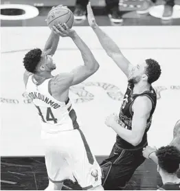  ?? MATT SLOCUM AP ?? Milwaukee’s Giannis Antetokoun­mpo, who scored 10 of his 32 points in overtime, goes up for a shot over Philadelph­ia’s Ben Simmons during the second half.