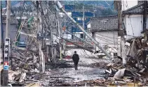  ?? REUTERS ?? A MAN makes his way along Asaichi-dori street, which burned down due to a fire following an earthquake, in Wajima, Japan, Jan. 4.