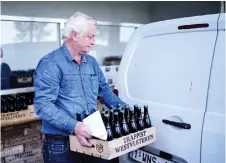  ??  ?? A customer carries a crate full of Westvleter­en beers while leaving the shop of the Saint-Sixtus abbey, in Westvleter­en.