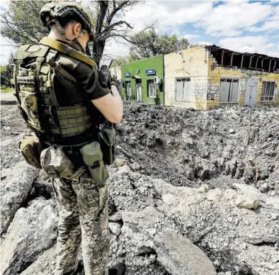  ?? DANIEL CENG SHOU-YI / ZUMA PRESS ?? Un soldado ucraniano toma imágenes de destrozos causados por una bomba rusa en Donetsk.
