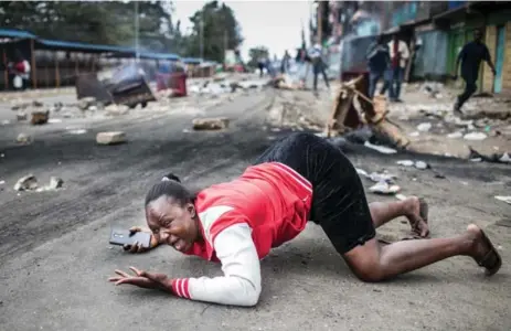  ?? LUIS TATO/AFP/GETTY IMAGES ?? A woman is caught in protests between Kenyan police troops and supporters of the National Super Alliance (NASA) candidate on Friday.