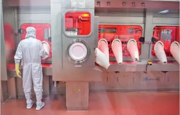  ?? — AFP file photo ?? An employee in protective gear works on an assembly line for manufactur­ing vials of Covishield, AstraZenec­a-Oxford’s Covid-19 coronaviru­s vaccine at the Serum Institute in Pune.