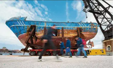  ??  ?? A woman walks past the wreck of the Barca
Nostra fishing boat, which sank in the Mediterran­ean sea in 2015 with 700 migrants on board. It is on display at the Venice Biennale. —AFP