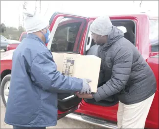  ?? Brodie Johnson • Times-Herald ?? The Northeast Arkansas Food Bank held a monthly commoditie­s distributi­on last week to continue aiding those who are in need. Mark Porter, left, hands a box of commoditie­s to James Copeland, with EACC, to be placed into a vehicle.*