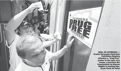  ??  ?? ‘SEAL OF APPROVAL’ — Ermita Barangay Chairman Felicisimo Rupinta attaches a “drug-free” poster to the door of a house, a practice the Commission on Human Rights is looking into. (Juan Carlo de Vela)