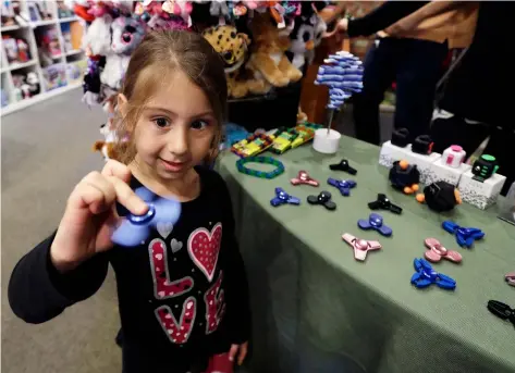  ?? CARLOS OSORIO/AP ?? Penelope Daversa, 4, plays with a fidget spinner at the Funky Monkey Toys store, in Oxford, Mich. Stores can’t keep them in stock and parents are going crazy trying to find them.