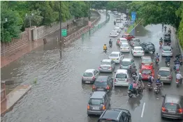  ?? — BIPLAB BANERJEE, PTI ?? Commuters ( above) wade through a waterlogge­d street after heavy rainfall in Noida on Saturday; Tourists ( right) make their way through a waterlogge­d street in New Delhi.