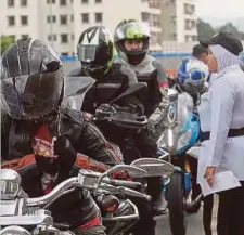  ??  ?? ANGGOTA polis trafik membuat pemeriksaa­n ke atas penunggang motosikal.