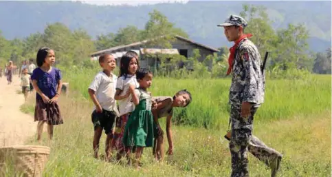  ?? AFP ?? LAUNGDON, Myanmar: Myo ethnic children look at a Myanmar border police in LaungDon, located in Rakhine State as security operation continue following the October 9, 2016 attacks by armed militant Muslims. —