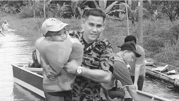  ??  ?? A Fire and Rescue personnel carries a child to a vehicle at Simpok.