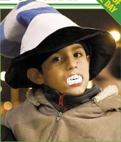  ?? AP ?? A child shows his support for Uruguay star player Luis Suarez by wearing toy plastic vampire’s teeth as he awaits arrival of Suarez at Carrasco Internatio­nal Airport on the outskirts of Montevideo Friday. The Uruguay star was banned by FIFA for four...