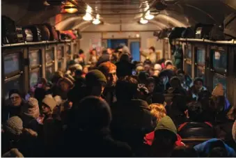  ?? AP PHOTO/BERNAT ARMANGUE ?? Displaced Ukrainians huddle aboard a Poland-bound train March 13 in Lviv, western Ukraine.