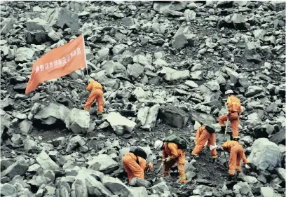  ?? PICTURE: REUTERS ?? Rescue workers search for survivors at the site of a landslide that occurred in Xinmo Village, Sichuan Province, China, on Saturday. The writing on the flag reads: ‘Chengdu Fire Department Rescue Team’.