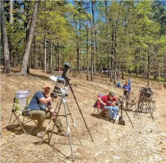 ?? (Submitted photo courtesy of Arkansas State Parks) ?? Visitors at Lake Ouachita State Park set up cameras along the edge of the lake Monday in hopes of capturing the eclipse.