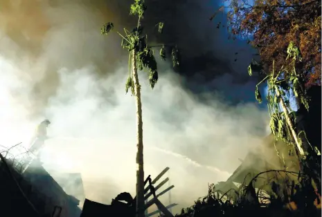  ?? (SUN.STAR FOTO/ALEX BADAYOS) ?? VANTAGE POINT. A fireman douses burning houses in Sitio Kawayan, Poblacion Pardo with water. The fire razed 91 houses and damaged seven other structures, says Pardo Barangay Captain Althea Lim.