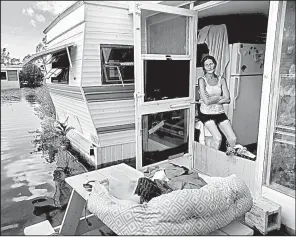  ?? AP/GERALD HERBERT ?? Cherie Ethier sits with her pets in her flooded mobile home Tuesday at an RV park in Naples, Fla.