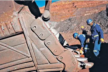  ??  ?? Workers repair an excavator at South Africa’s Sishen open cast mine, operated by Kumba Iron Ore, part of Anglo American