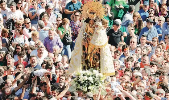  ?? EFE ?? Fervor y devoción. Los valenciano­s aclaman a la Virgen mientras dos niños alcanzan a la Mare de Déu de mano en mano sobre las cabezas
