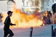  ?? — AFP ?? A man runs in front of a burning garbage on Thursday in Marseille, southern France, on the sideline of a demonstrat­ion of high school students protesting against education reforms.