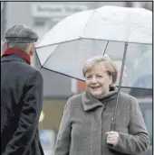  ?? Michael Sohn The Associated Press ?? German Chancellor Angela Merkel holds an umbrella as she arrives at the Berlin Wall Memorial on Saturday.