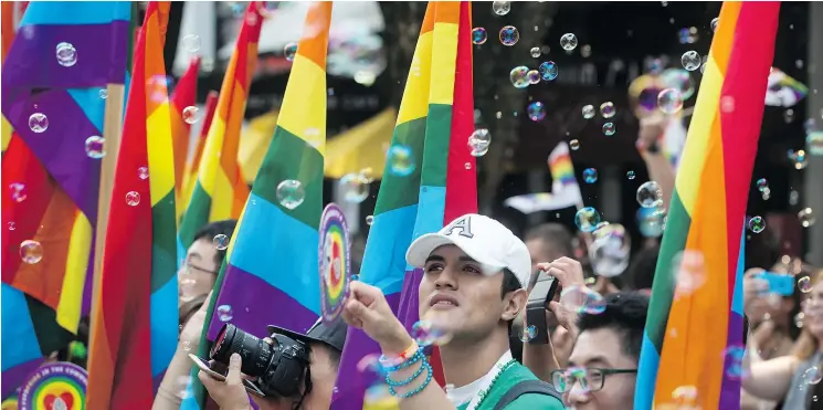  ?? — THE CANADIAN PRESS FILES ?? Bubbles float in the air as people holding rainbow flags participat­e in the Vancouver Pride Parade last year. The 2018 parade is on Sunday.