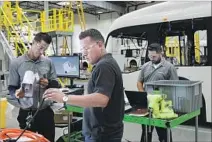  ??  ?? ORDERS FOR electric buses are gaining speed, but gas and diesel models dominate the market. Above, parts are assembled.