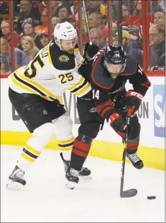  ?? Gerry Broome / Associated Press ?? The Bruins’ Brandon Carlo and Hurricanes’ Justin Williams skate for the puck during the second period in Game 3 of the Stanley Cup Eastern Conference final series on Tuesday in Raleigh, N.C.