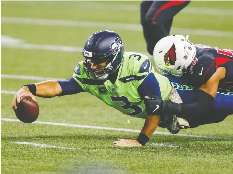  ?? JOE NICHOLSON/ USA TODAY SPORTS ?? Seahawks QB Russell Wilson reaches out for extra yardage as he's tackled during Thursday night's NFL contest. If would really dampen the mood for the NFL if a major star such as Wilson had to miss a big game late in the season due to COVID-19, Scott Stinson writes.