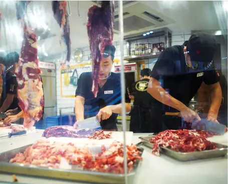  ??  ?? Chinese workers cut beef at a restaurant in Shenzhen. China is looking to diversify its protein sources as African swine fever hits its domestic hog herd.