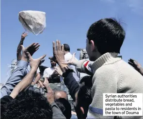  ??  ?? Syrian authoritie­s distribute bread, vegetables and pasta to residents in the town of Douma