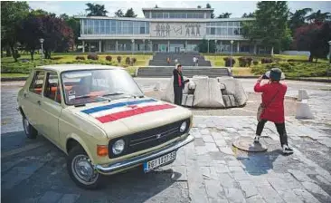  ??  ?? Top: Jovana Stojiljkov­ic, manager of the Yugotour agency, drives a Yugoslav era popular car ‘Zastava 101’ in Belgrade.
Above: Visitors take pictures near ‘Zastava 101’, in front of the Museum of Yugoslavia in Belgrade.