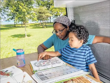  ?? BRIAN CASSELLA/CHICAGO TRIBUNE ?? Tiana Kubik works on a lesson with her son, Griffin, 6, inside their van while parked at Chicago’s Montrose Harbor.