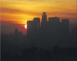  ?? Luis Sinco Los Angeles Times By John Myers ?? THE SUN sets behind downtown Los Angeles in December. Daylight saving time was first applied in a uniform fashion across the United States in 1966.