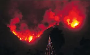  ??  ?? A Christmas tree stands as a lone sentinel in the front yard of an evacuated home in Carpinteri­a, Calif. on Monday.