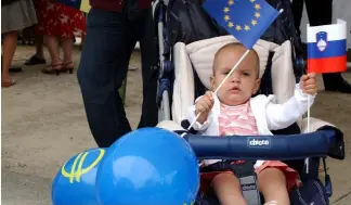  ?? ?? A baby girl waves the European flag along with the Slovenian one while attending a celebratio­n in Brussels, July 11, 2006.