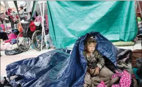  ?? HANS-MAXIMO MUSIELIK / AP ?? A girl who traveled with the annual caravan of Central American migrants awakens Tuesday where the group set up camp to wait for access to request asylum in the U.S., outside the El Chaparral port of entry building at the U.s.-mexico border in Tijuana,...